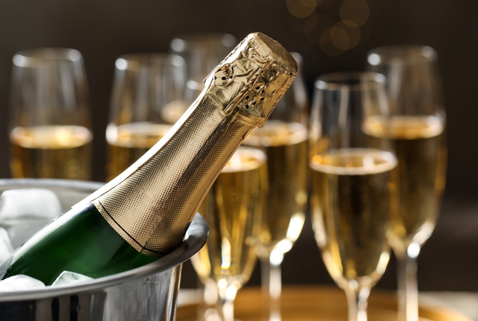 Flasche Champagner in Eimer mit Eis und Gläsern auf unscharfem Hintergrund